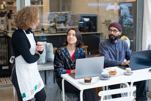 A dynamic outdoor café setting in Portugal with people working on laptops and a waitress serving.